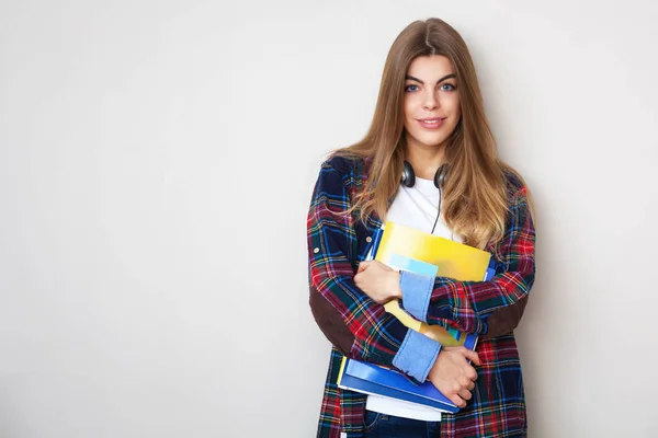 Junge schöne Studentin mit Büchern, die an der Wand stehen. — Stockfoto