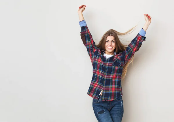 Gelukkig jonge vrouw in geruite hemd poseren tegen muur. — Stockfoto