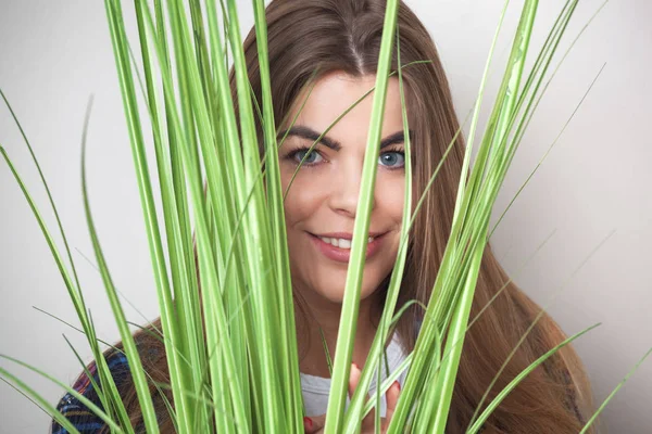 Retrato de bela jovem mulher escondida atrás de folhas verdes . — Fotografia de Stock