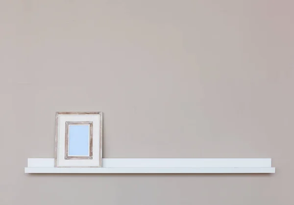 Małe białe półki z ramki na zdjęcia na ścianie. — Zdjęcie stockowe