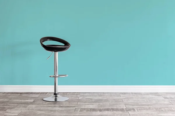 Black bar stool in front of wall.