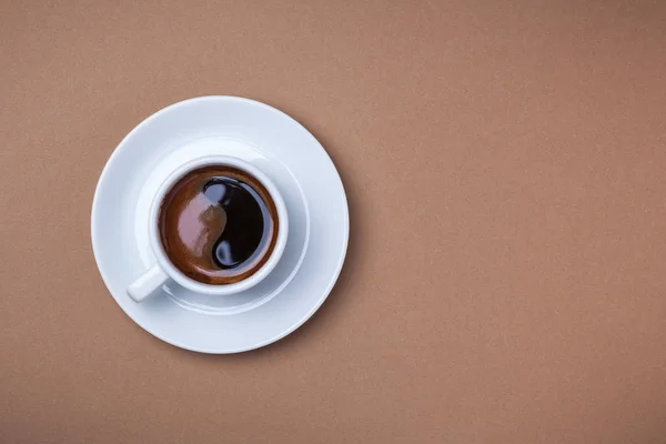 Kopje espresso met schotel op bruine achtergrond. — Stockfoto