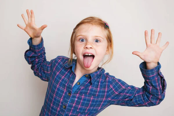 Zabawny Ruda dziewczynka w niebieski plaid shirt pozowanie przed wal — Zdjęcie stockowe