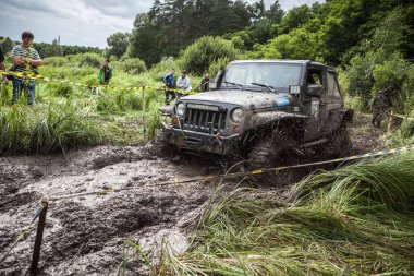 Katılımcı Jeep üzerinde derin çamurlu çukur geçer.