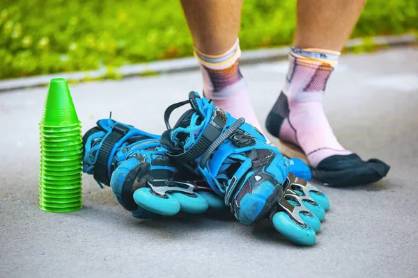 Blauwe rolschaatsen met slalom cones en roller sokken op mannelijke le — Stockfoto