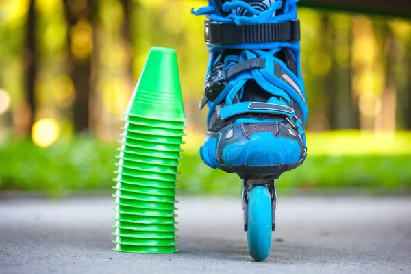 Patins à roulettes bleus avec cônes de slalom couchés sur asphalte . — Photo