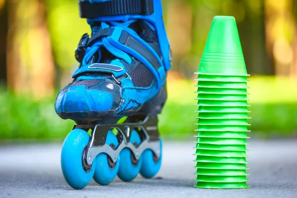 Patins à roulettes bleus avec cônes de slalom couchés sur asphalte . — Photo