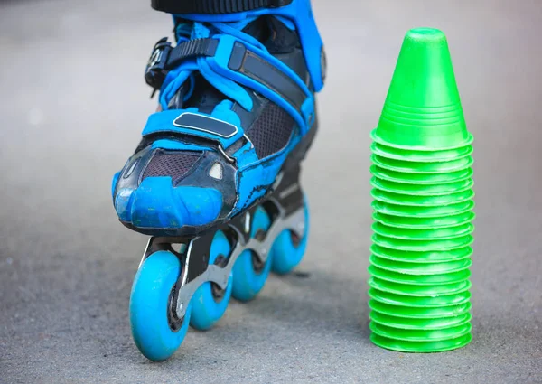 Patins à roulettes bleus avec cônes de slalom couchés sur asphalte . — Photo