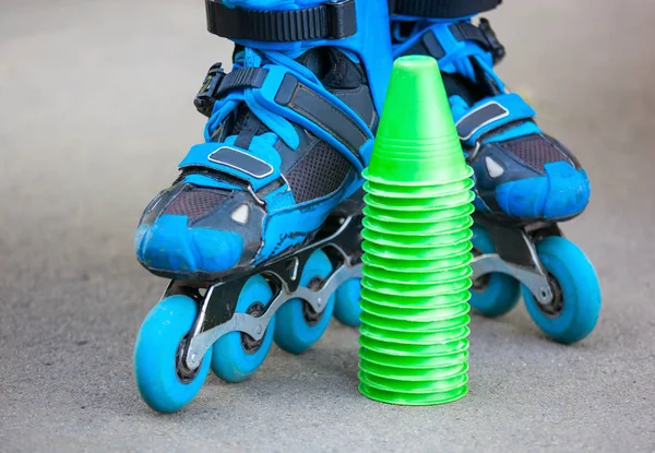 Patins à roulettes bleus avec cônes de slalom couchés sur asphalte . — Photo