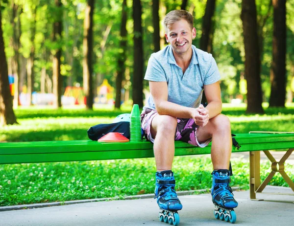 Retrato de rodillo masculino guapo feliz sentado en el banco en el p —  Fotos de Stock