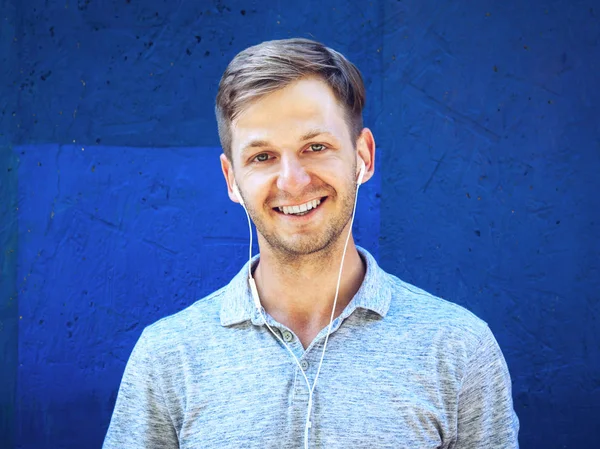 Retrato de joven guapo feliz contra la pared azul . —  Fotos de Stock