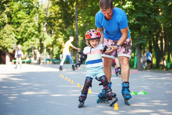 Bonito menino com instrutor de patinação em linha no parque — Fotografia de Stock