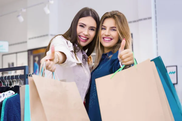 Hermosas mujeres jóvenes con bolsas de compras mostrando los pulgares hacia arriba . —  Fotos de Stock