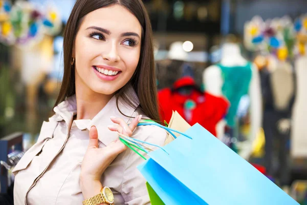 Retrato de una hermosa joven con bolsas de compras en ropa —  Fotos de Stock