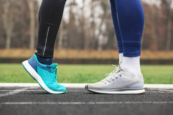 Foto recortada de un hombre y una mujer piernas en zapatillas de correr cerca de — Foto de Stock