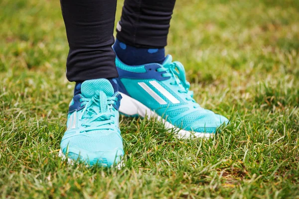 Foto de las piernas de una mujer en zapatos de correr de pie sobre la hierba . — Foto de Stock