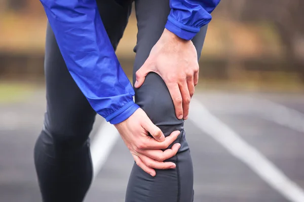 Coup de feu recadré d'un jeune coureur tenant son genou blessé tout ru — Photo