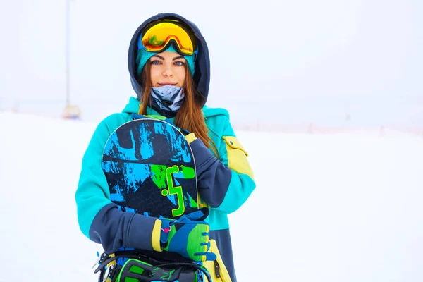 Mooie jonge snowboarder meisje houden snowboard. — Stockfoto