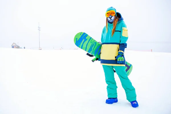 Beautiful young snowboarder girl holding snowboard. — Stock Photo, Image