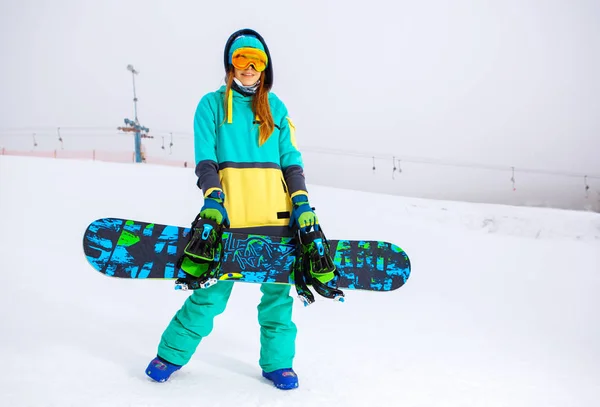 Beautiful young snowboarder girl holding snowboard. — Stock Photo, Image