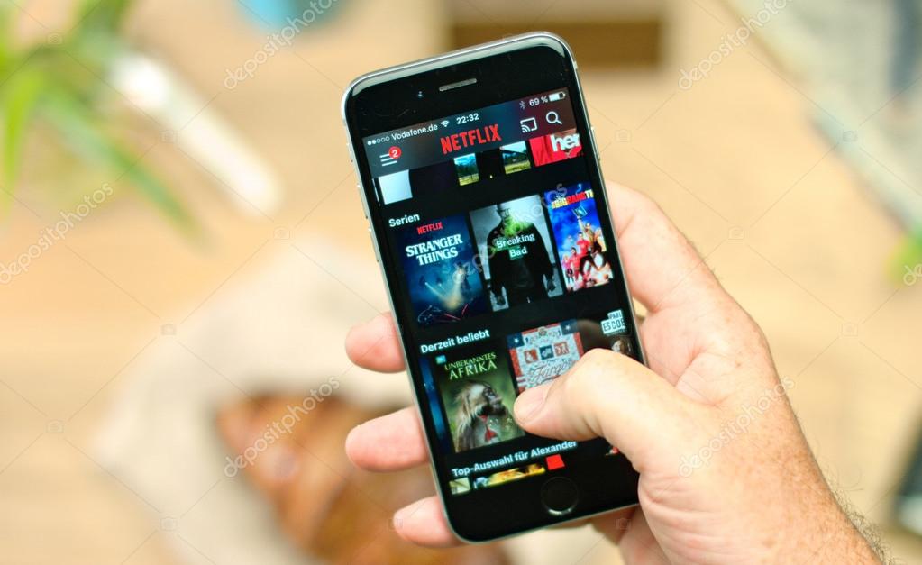 AACHEN, GERMANY - 18. October 2016 : Netflix app on Apple iPhone 6s. Young man is browsing the movie video library what to watch.