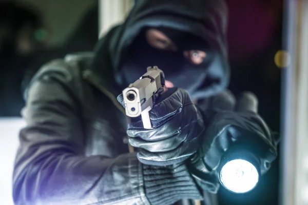 Masked burglar with pistol gun