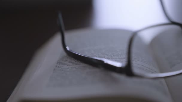 Старая книга на рабочем столе с современными очками — стоковое видео