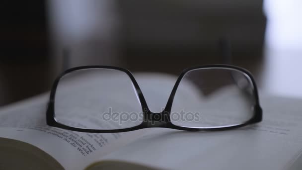 Стара книга на робочому столі з сучасними окулярами — стокове відео