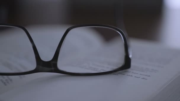 Livro velho na área de trabalho com óculos modernos — Vídeo de Stock