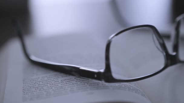 Livro velho na área de trabalho com óculos modernos — Vídeo de Stock