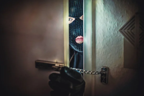 Masked burglar with crowbar breaking and entering into a victim's home — Stock Photo, Image