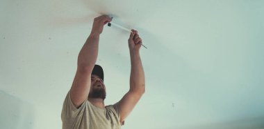 Painter working with paint roller and brushes to paint the room clipart