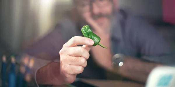 Creative designer looks at green pepper — Stock Photo, Image