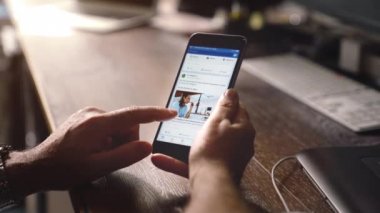 genç adam facebook app apple iPhone'da 6s artı ofiste kullanır 