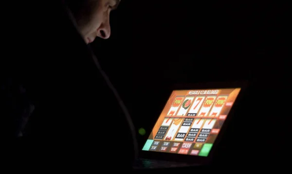 Hombre delante de la máquina tragaperras de casino en línea en el ordenador portátil — Foto de Stock
