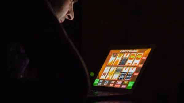 Hombre delante de la máquina tragaperras de casino en línea en el ordenador portátil — Foto de Stock