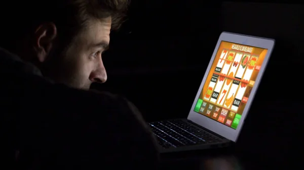 Man in front of online casino slot machine on laptop — Stock Photo, Image