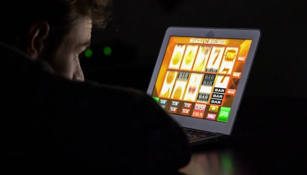 Man in front of online casino slot machine on laptop — Stock Photo, Image