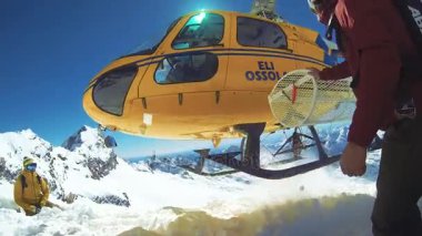 Alagna Valsesia'da, Piemont, İtalya - 28 Mart 2015: Snowboard actionsportlers Dağları nın üstündeki bir helikopterle düştü. Güneş mavi gökyüzünde parlıyor. Dağ silsilesi içinde geçmiş karla kaplı. Görüntüleri içeren markalar, logolar 