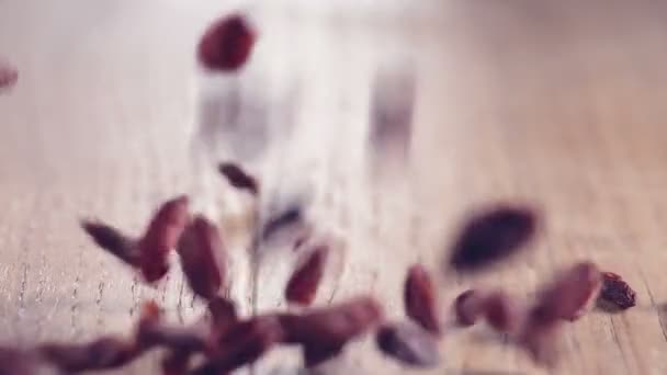 Lot de Baies de Goji authentiques Ralenti tombant sur une table en bois, gros plan 