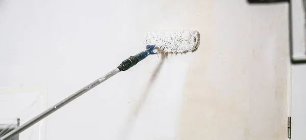 Close up of painter working with paint roller and brushes to paint the room in white colors. dig - do it yourself — Stock Image Close Painter Working Paint Roller Brushes Paint Room White Colors Stock Image