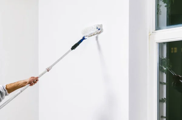 Close up of painter working with paint roller and brushes to paint the room in white colors. dig - do it yourself — Stock Image Close Painter Working Paint Roller Brushes Paint Room White Colors Royalty Free Stock Images