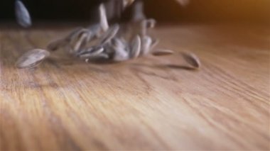 Bazı Ayçekirdeği ahşap masaya döküldü. Ağır çekimde kameraya doğru kayar.