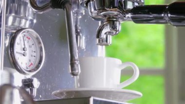 Klasik kahve makinesinden küçük beyaz fincan içine dökme espresso. Yakın çekim Shot.