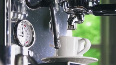 Klasik kahve makinesinden küçük beyaz fincan içine dökme espresso. Yakın çekim Shot.