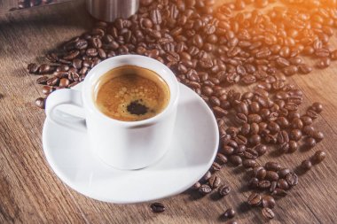 Beyaz kahve fincanı kahve çekirdekleri ile ahşap tabloda Espresso ile dolu. Tablo üst görünüm.