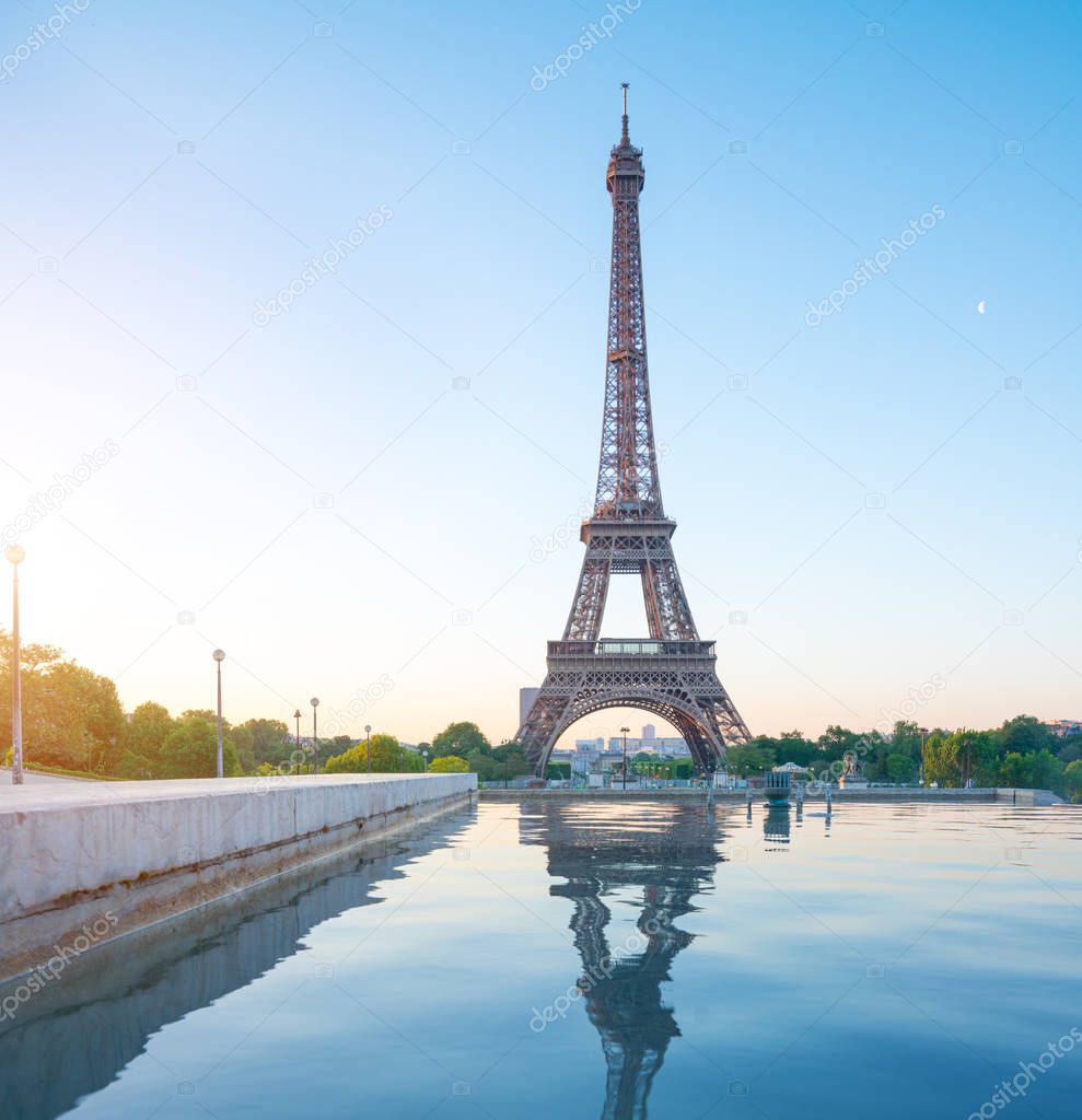 the famous paris eiffel tower on a sunny day with some morning sunshine reflects in blue water