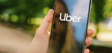 Uber sürücüsü akıllı telefonu arabada tutuyor. Uber bir Amerikan şirketi.