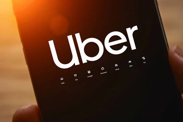 Conductor de Uber sosteniendo smartphone en coche. Uber es una compa americana —  Fotos de Stock