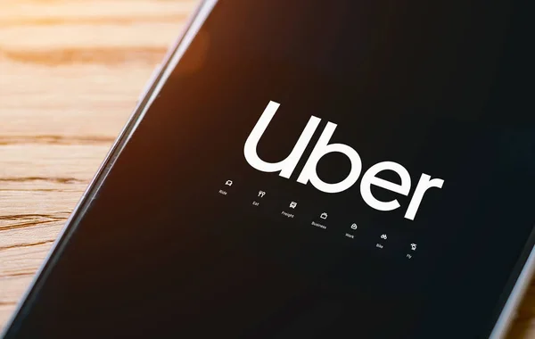Kierowca Uber trzyma smartfona w samochodzie. Uber to amerykańska kompania. — Zdjęcie stockowe
